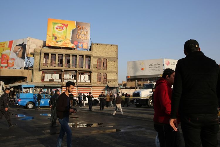 Warga berjalan melewati lokasi dua serangan bom bunuh diri yang menewaskan 26 orang di Baghdad pada Senin (15/1/2018). (AFP/Sabah Arar)