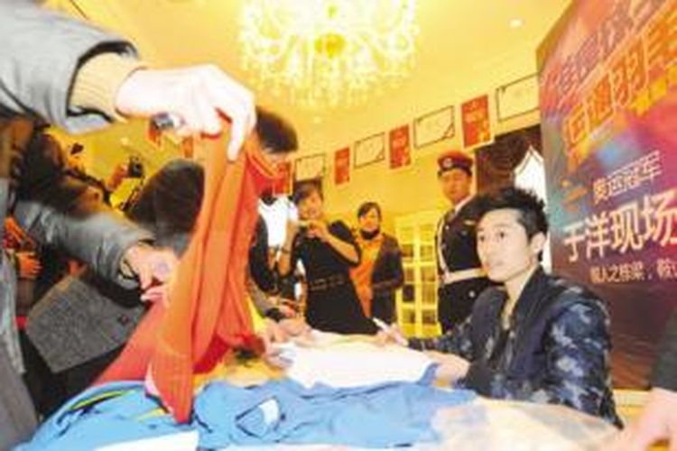 Pebulu tangkis nomor ganda putri asal China, Yu Yang (kanan) menandatangani jersey pada kegiatan promosi bulu tangkis di kampung halamannya, Anshan, Liaoning, Senin (23/12/2013).
