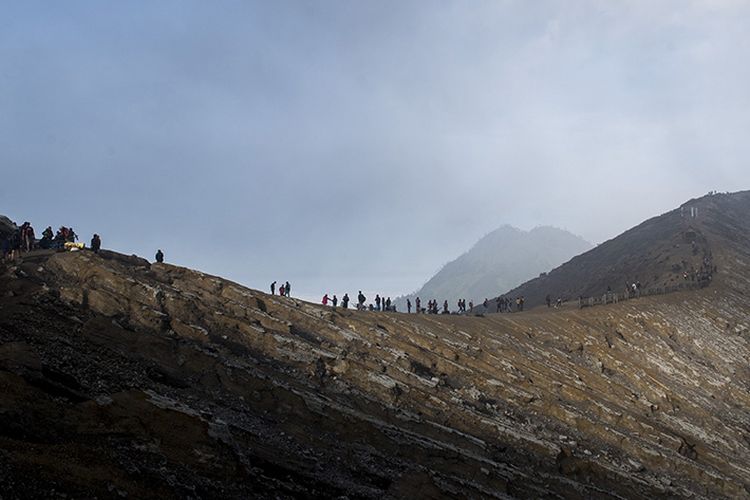 Ratusan wisatawan menikmati pemandangan dari puncak Gunung Ijen, Banyuwangi, Jawa Timur, Sabtu (23/6/2018). Kawah Ijen dengan kedalaman 200 meter menjadi salah satu dari dua lokasi di dunia yang memiliki fenomena api biru selain Islandia, membuat Ijen menjadi tujuan utama pendaki dari berbagai pelosok negeri hingga mancanegara.