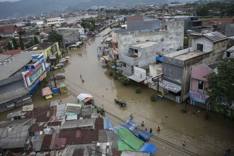 Warga melintasi banjir di Jalan Raya Dayeuhkolot, Kabupaten Bandung, Jawa Barat, Kamis (7/3/2019). Sedikitnya delapan kecamatan dengan 5.271 kepala keluarga terdampak banjir di kawasan Bandung Selatan tersebut akibat luapan Sungai Citarum dan intensitas curah hujan yang tinggi.