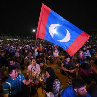 Pendukung kandidat oposisi Mahathir Mohamad berkumpul di sebuah lapangan untuk menyaksikan hasil siaran langsung dari komisi pemilihan umum ke-14, di Kuala Lumpur, Kamis (10/5/2018) dini hari. (AFP/Mohd Rasfan)