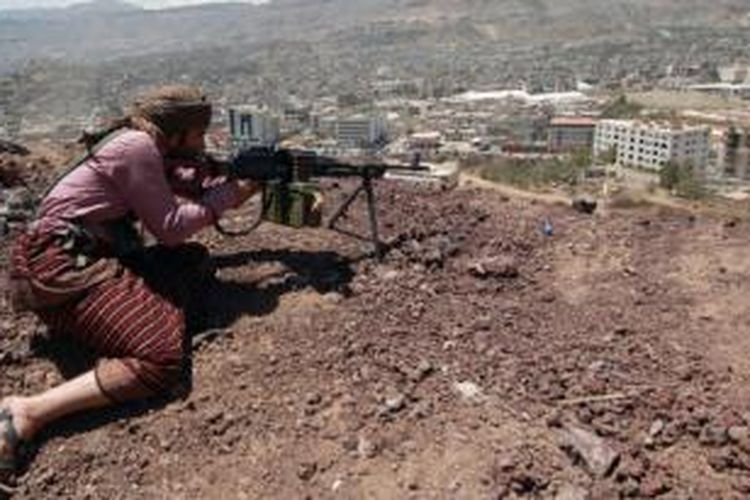 Seorang anggota pemberontak Syiah mengarahkan senapan mesinnya ke ibu kota Sanaa dari atas sebuah bukit. Pemberontak dikabarkan telah menguasai istana presiden dan menyerang kediaman resmi Presiden Abdurabuh Mansur Hadi, Selasa (20/1/2015).