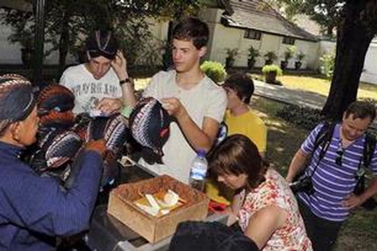 Wisatawan asal Belanda membeli Blangkon di Keraton Yogyakarta, Yogyakarta, Kamis (26/7/2012). Selama bulan Ramadhan, pengunjung Keraton Yogyakarta didominasi oleh wisatawan asing dengan jumlah berkisar 600 pengunjung per hari sedangkan wisatawan domestik turun dari sedikitnya 1.500 pengunjung per hari menjadi sekitar 300 pengunjung per hari.
