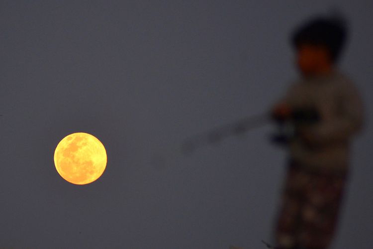 Seorang bocah memancing ikan saat berlangsungnya fenomena Supermoon di Pelabuhan Perikanan Samoedra, Koetaraja, Banda Aceh, Aceh, Selasa (19/2/2019). Badan Meteorologi, Klimatologi, dan Geofisika (BMKG) melansir fenomena Supermoon kali ini atau disebut juga Super Snow Moon terjadi saat bulan berada pada titik perige terdekat yakni 363.300 km dari bumi sehingga bulan terlihat 14 persen lebih besar dan 30 persen lebih terang dari bulan purnama.