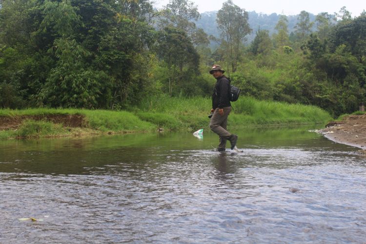 Salah satu pengunjung melintasi sungai saat menuju Air Terjun Coban Talun, Kota Batu, Minggu (6/1/2019)