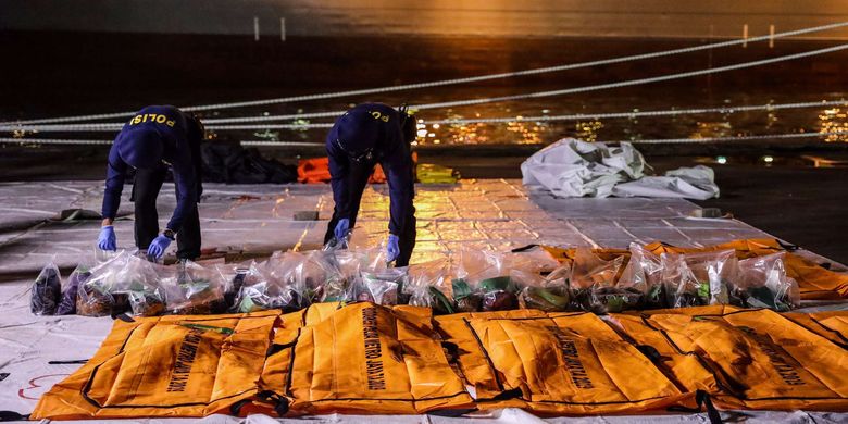 Anggota kepolisian mengangkat kantong jenazah berisi objek temuan dari lokasi jatuhnya pesawat Sriwijaya Air SJ 182 rute Jakarta-Pontianak pada hari ketujuh Operasi SAR pesawat tersebut di Dermaga JICT 2, Tanjung Priok, Jakarta Utara, Jumat (15/1/2021).