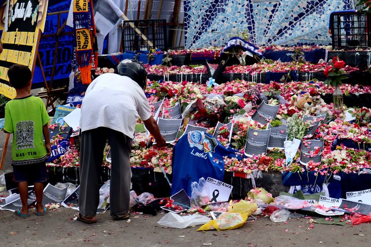 Seorang laki-laki meletakkan tulisan ditumpukan bunga di hari kedua pasca tragedi yang terjadi pada pekan ke-11 Liga 1 2022-2023 seusai pertandingan bertajuk Derbi Jawa Timur, Arema FC melawan Persebaya Surabaya di Stadion Kanjuruhan Kepanjen, Kabupaten Malang, Senin (3/10/2022) siang.