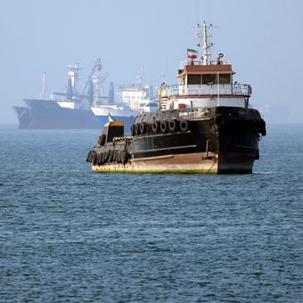 Kapal penarik Basim berbendera Iran berlayar dekat kapal yang berlabuh di Selat Hormuz. Foto ini dipotret dari Bandar Abbas, Iran selatan, 4 Mei 2026 ketika perang Iran masih berkecamuk.
