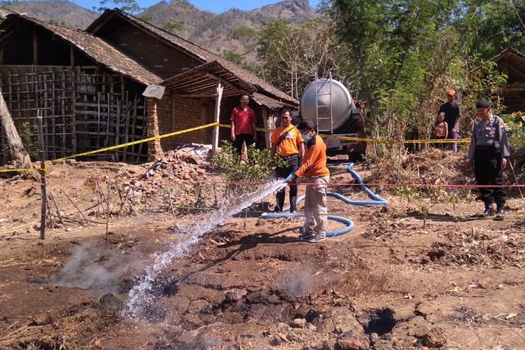 Petugas BPBD Kabupaten Ponorogo memadamkan api yang keluar dari tanah di Dukuh Ringin Surup, Desa Kupuk, Kecamatan Bungkal, Kabupaten Ponorogo, Jawa Timur.