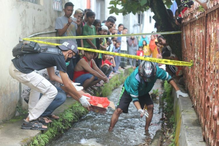 Polisi dibantu warga mengevakuasi jasad bayi merah yang dibuang di saluran selokan di Kelurahan Sayang, Cianjur, Jawa Barat, Minggu (31/1/2021).