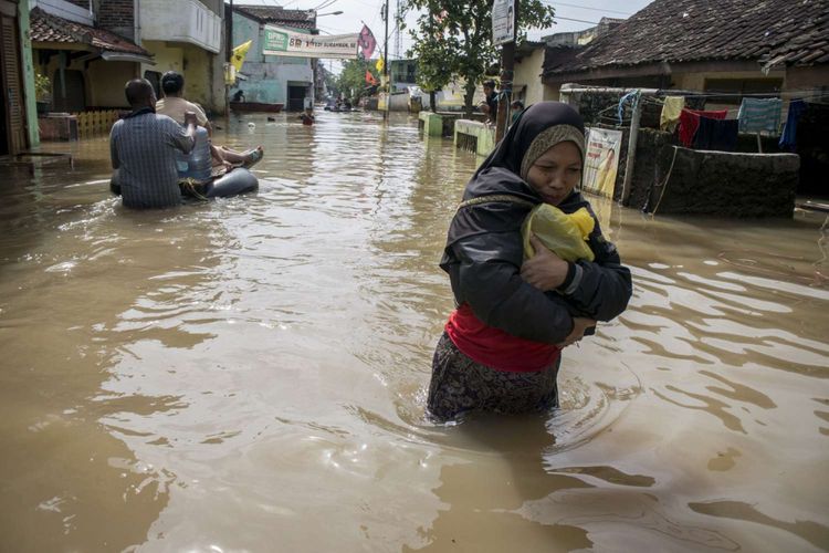 Warga berjalan melintasi banjir di Bojong Asih, Kabupaten Bandung, Jawa Barat, Jumat (8/3/2019).