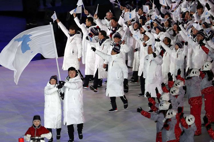 Hwang Chung Gum dan Won Yunjong dari Korea membawa bendera Persatuan Korea dalam upacara pembukaan Olimpiade Musim Dingin 2018 Pyeongchang di Stadion Olimpiade Pyeongchang, Pyeongchang, Korea Selatan, Jumat (9/2/2018). Dalam parade pembukaan tersebut, para atlet dari Korea Selatan dan Korea Utara berjalan berdampingan dengan membawa bendera unifikasi kedua negara, yang menjadi peristiwa emosional karena selama ini kedua negara dikenal bersitegang secara politik.