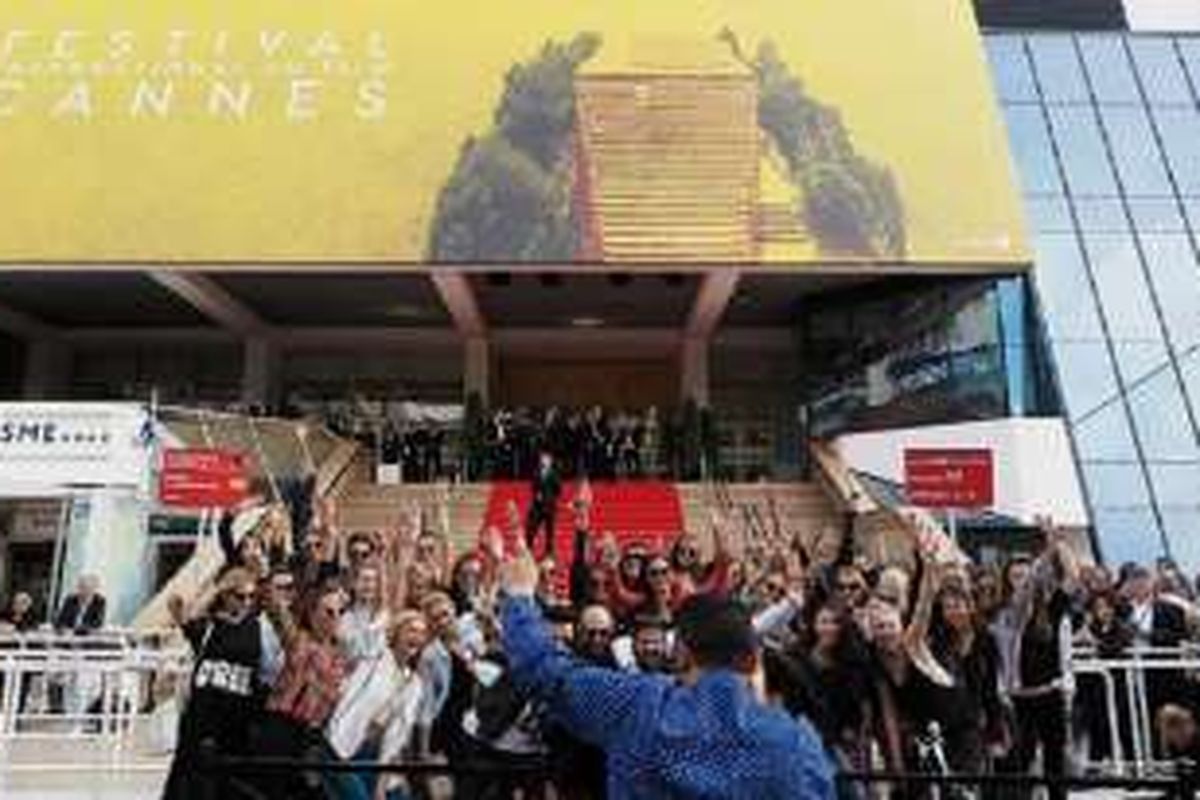 Serombongan pengunjung berpose di depan Palais des Festivals, gedung utama penyelenggaraan Festival Film Cannes, Perancis. 