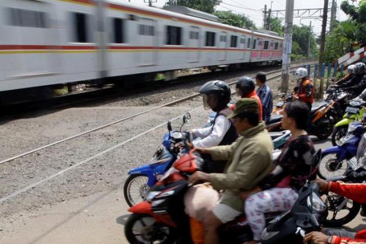 Pengendara motor berhenti di perlintasan kereta api di sekitar Pasar Bintaro, Pesanggrahan, Jakarta Selatan, Kamis (4/4/2013). Pertemuan lalu lintas dari empat arah di pintu perlintasan itu menjadi penyebab kemacetan. Kondisi ini tentunya menyebabkan kawasan itu rawan kecelakaan yang melibatkan kereta api.
