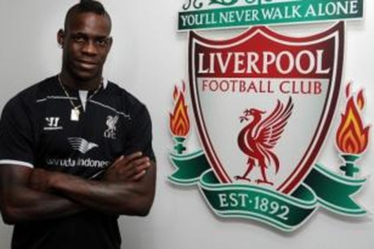 Penyerang Mario Balotelli, berfoto di sebelah logo Liverpool, di Melwood, Senin (25/8/2014), usai menandatangani kontrak dengan klub itu. Dengan begitu, Balotelli resmi pindah dari AC Milan ke Liverpool.