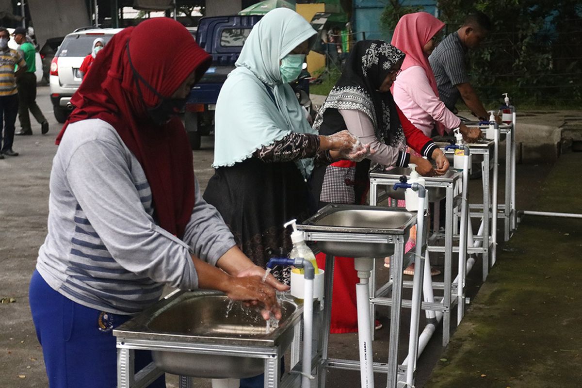 Sejumlah pedagang dan pengunjung mencuci tangan di wastafel di Pasar Induk Osowilangun Surabaya (PIOS), Surabaya, Jawa Timur, Sabtu (28/3/2020). Manajemen Pasar Induk Osowilangun Surabaya (PIOS) selain memasang 20 unit tempat cuci tangan (wastafel) dan 50 botol besar hand sanitizer di sejumlah titik di lokasi PIOS juga membagikan sekitar 400 botol kecil hand sanitizer kepada para pengunjung pasar tersebut sebagai upaya untuk mencegah penyebaran virus Corona (COVID-19).