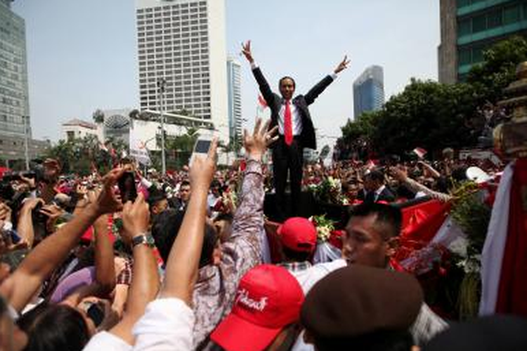Presiden Republik Indonesia Joko Widodo menyapa warga saat diarak menggunakan kereta kencana ketika berada di kawasan Bundaran Hotel Indonesia, Jakarta Pusat, Senin (20/10/2014).