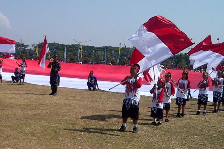 Aremania dan anggota TNI membentangkan bendera merah putih raksasa dalam upacara HUT TNI ke 68 di lapangan Rampal, Malang, Jawa Timur, Sabtu (05/10/2013).