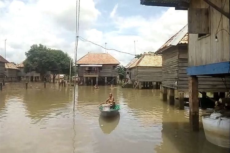 Seorang nenek harus menggunakan perahu saat hendak melintasi banjir. Air banjir sendiri masih mencapai 30 cm hingga 1 meter sete;ah sebelunya sempat mencapai satu setengah meter.