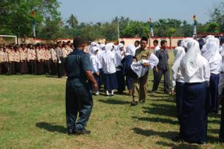 Seorang siswi SMP pingsan dibopong keluar dari barisan peserta upacara HUT Ke-69 RI di Kendal, Jawa Tengah, Minggu (17/8/2014).