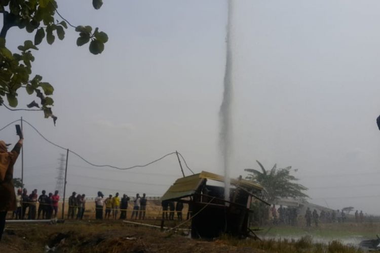 Nampak seorang warga berswafoto di semburan air disertai gas yang muncul di area persawahan Desa Sidolaju, Kecamatan Widodaren, Kabupaten Ngawi, Jawa Timur, Rabu ( 8/8/2018).