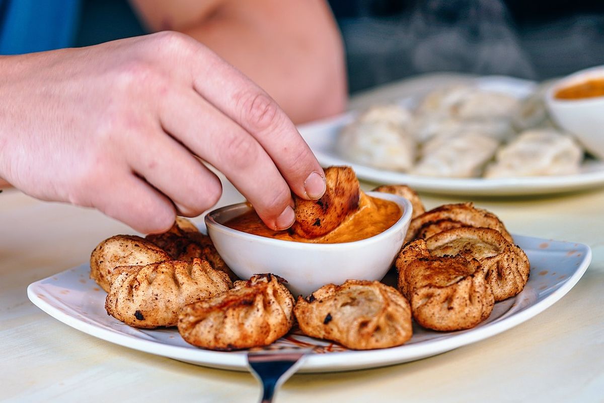 Ilustrasi makan dimsum goreng dengan saus cocolan. 