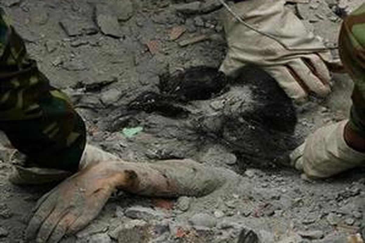 Tentara China menggunakan tangan mereka untuk mengeluarkan sesosok jenazah dari reruntuhan sebuah  gedung di kota Dujiangyan, provinsi Sichuan, 17 Mei 2008.   