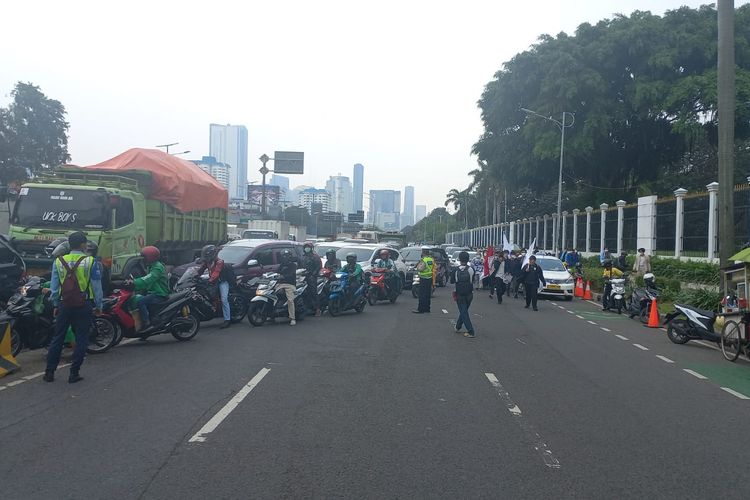 Petugas kepolisian mengarahkan pengendara masuk ke Jalur Busway Jalan Gatot Subroto menyusul adanya aksi demonstrasi di depan Gedung DPR/MPR RI, Senin (11/4/2022).