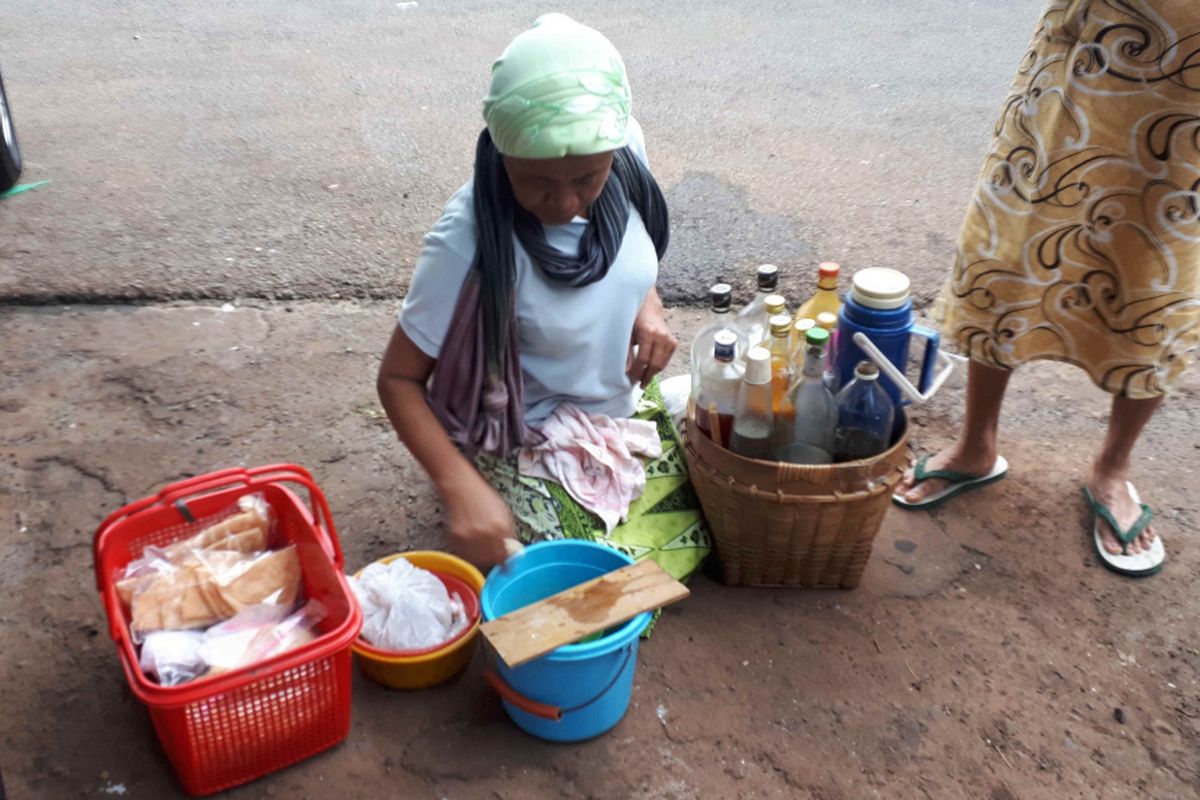 Nanik (54), penjual jamu keliling sedang melayani pelanggan setianya di kawasan Palmerah, Jakarta Barat, Kamis (31/1/2019).