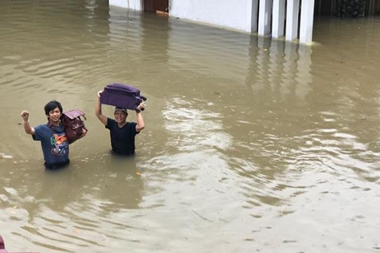 Vokalis DMASIV Rian Ekky Pradipta menerobos banjir di kawasan Kemang, Jakarta Selatan. 