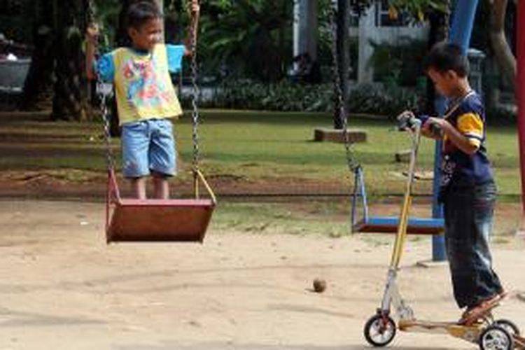 Anak-anak memanfaatkan taman bermain di Taman Menteng, Jakarta.
