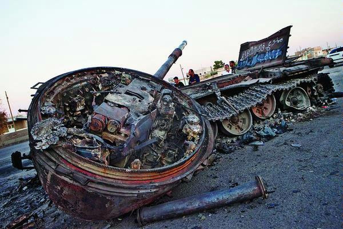Bangkai tank tentara Suriah yang hancur teronggok di  Khan-al Sible, Idlib, di tepi jalan antara Aleppo dan Damaskus, Rabu (4/7). Menteri Luar Negeri Amerika Serikat Hillary Clinton mendesak Perserikatan Bangsa-Bangsa memberi sanksi lebih keras kepada Suriah, saat seorang jenderal top Suriah membelot ke Turki, Jumat. 