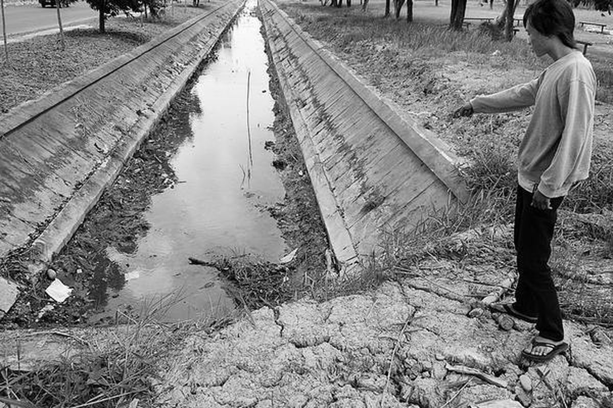 Seorang warga Alang-Alang Lebar menunjukkan saluran irigasi dari anak Sungai Musi yang airnya mulai mengering, Rabu (24/6). Meski belum memasuki puncak kemarau, berbagai sumber air mengering