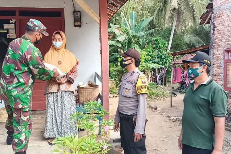 Salah satu anggota Babinsa Koramil Tugu Trenggalek beserta bhabinkamtibmas dan perangkat desa Prambon, memberi bantuan kepada warga yang terdampak PPKM Darurat Covid-19, Minggu (08/08/2021).