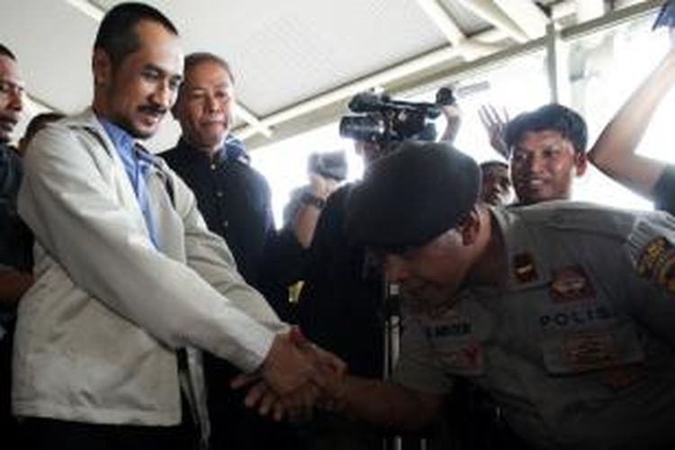 Perwira polisi menyalami ketua KPK nonaktif, Abraham Samad sambil menunduk saat di Bandara Internasional Sultan Hasanuddin, Makassar, Selasa (24/2/2015).