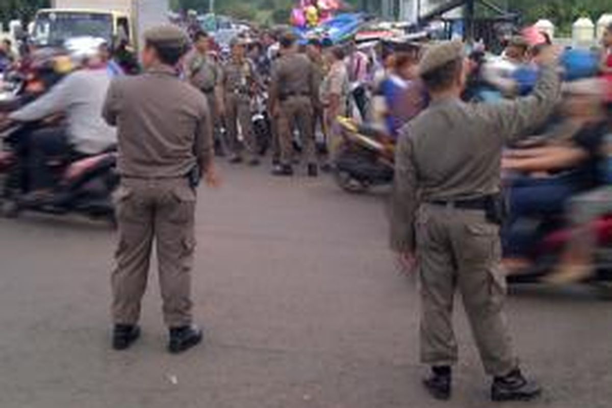 Petugas Satuan Polisi Pamong Praja melakukan penertiban PKL di sepanjang jalur inspeksi kawasan Duren Sawit dan Jatinegara Jakarta Timur. Selasa (17/6/2014).