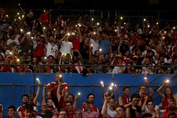 Fan yang menghadiri laga UEFA Nations League 2022-2023 Austria vs Denmark menyalakan ponsel untuk menerangi Stadion Ernst-Happel, pada 6 Juni 2022. Laga Austria vs Denmark sempat tertunda gara-gara Stadion Ernst-Happel mati lampu.