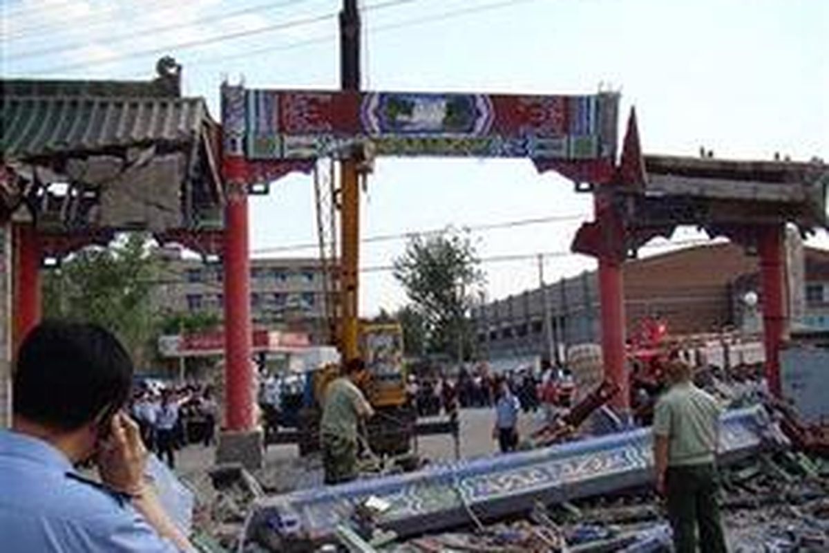 Para pekerja berusaha membersihkan puing-puing bangunan yang hancur akibat gempa di  Henan