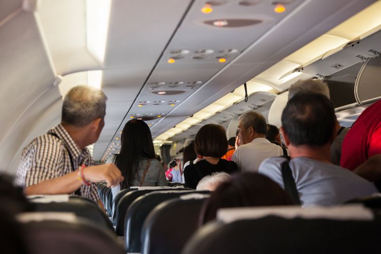 Ilustrasi penumpang pesawat yang berdiri menunggu pintu keluar pesawat dibuka. 