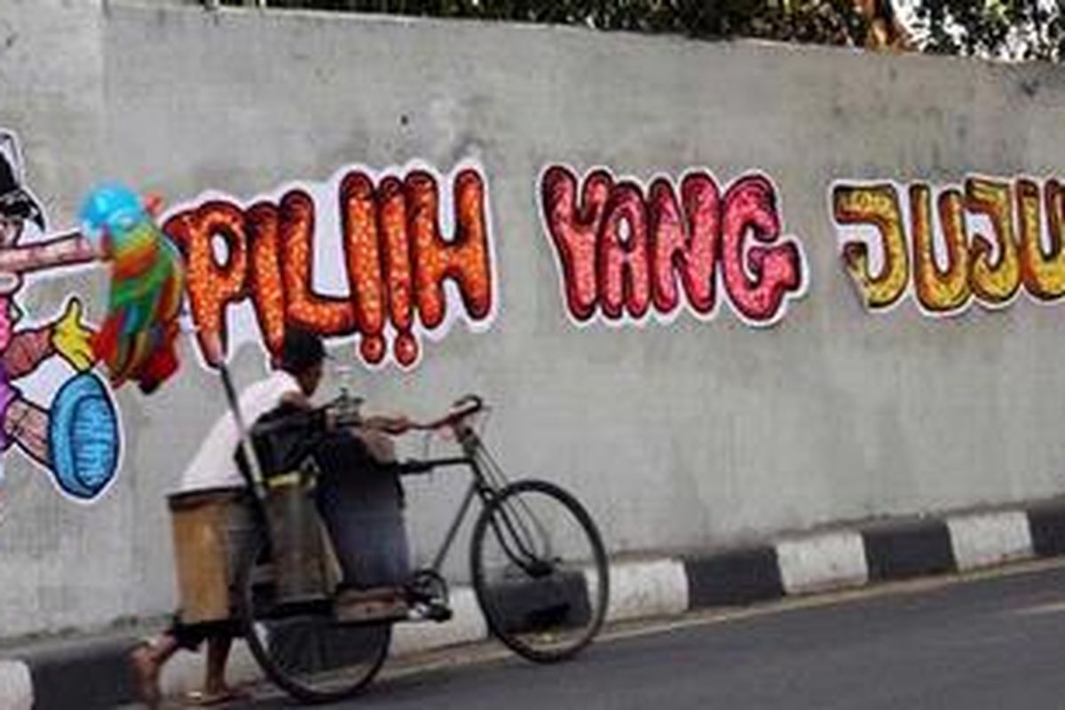 Pengendara melintas di depan sebuah lukisan tembok (mural) bertema pilkada di Jalan Sultan Agung Jakarta Selatan, Minggu (1/7/2012).   