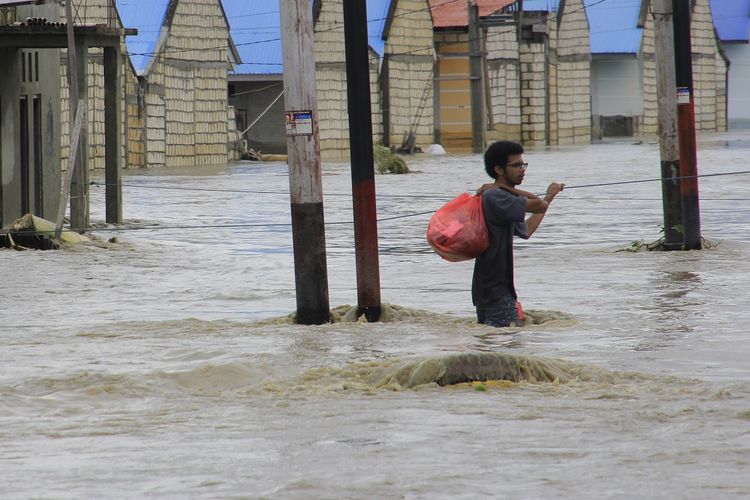 Seorang warga menyelamatkan barang berharga miliknya dari rumahnya yang terendam banjir akibat banjir bandang Sentani Jayapura, Papua, Senin (18/3/2019). Berdasarkan data BNPB tercatat sebanyak 77 orang meninggal dunia, 43 orang belum ditemukan, 74 orang luka-luka dan 4.226 orang mengungsi akibat banjir bandang yang melanda Sentani pada Sabtu (16/3). ANTARA FOTO/Gusti Tanati/ama.