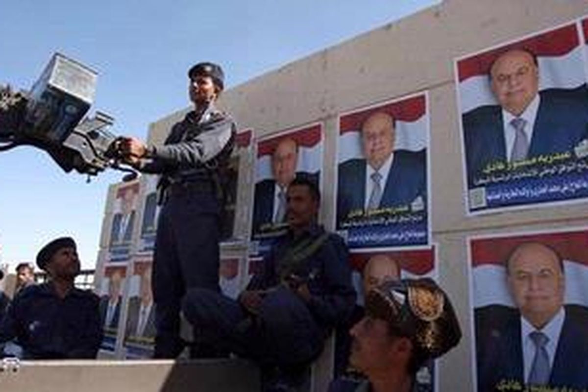 Polisi Yaman bersiaga dengan latar belakang poster-poster calon tunggal pemilihan presiden, Abed Raboo Mansour Hadi, Senin (20/2/2012).  