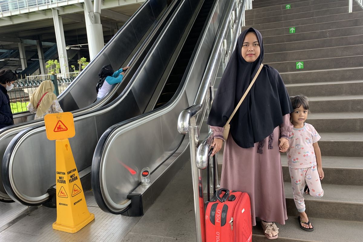 Seorang ibu bernama Widayanti (27) terlihat menggotong koper dan memegangi anaknya yang berusia empat tahun saat turun dari tangga manual Stasiun Bekasi karena eskalator masih belum beroperasi, Rabu (7/2/2024).