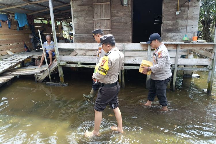 Anggota Polsek Bunut saat memantau kondisi banjir dan menyalurkan bantuan sosial kepada warga terdampak, di Desa Petani, Kecamatan Bunut, Kabupaten Pelalawan, Riau, Selasa (16/1/2024).