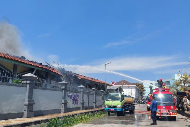 Petugas pemadam kebakaran mencoba melakukan pemadaman dengan disaksikan warga