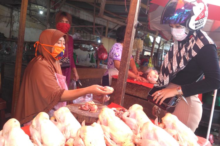 Romlah, pedagang ayam potong di Pasar Gintung, Bandar Lampung melayani pembeli, Rabu (8/4/2020). Para pedagang mengaku harga ayam potong turun lantaran banyak yang membatalkan pernikahan di tengah pandemi corona.