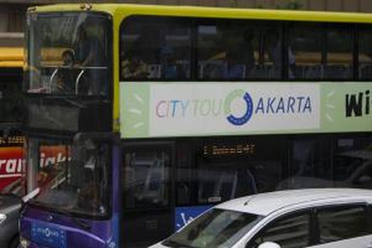 Wisawatan naik bus wisata melewati kawasan Jalan MH Thamrin, Jakarta Pusat, Jumat (15/1/2016). Aksi teror dan serangan bersenjata di perempatan Jalan MH Thamrin Kamis lalu telah menumbuhkan kesadaran masyarakat untuk bersama-sama bangkit melawan terorisme.