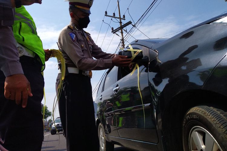 Petugas kepolisian dari Satlantas Polres Blitar memasang pita janur kuning pada kendaraan pemudik yang melakukan pelanggaran di Jalan Kusumabangsa, Kanigoro, Kabupaten Blitar, Minggu (24/4/2022)