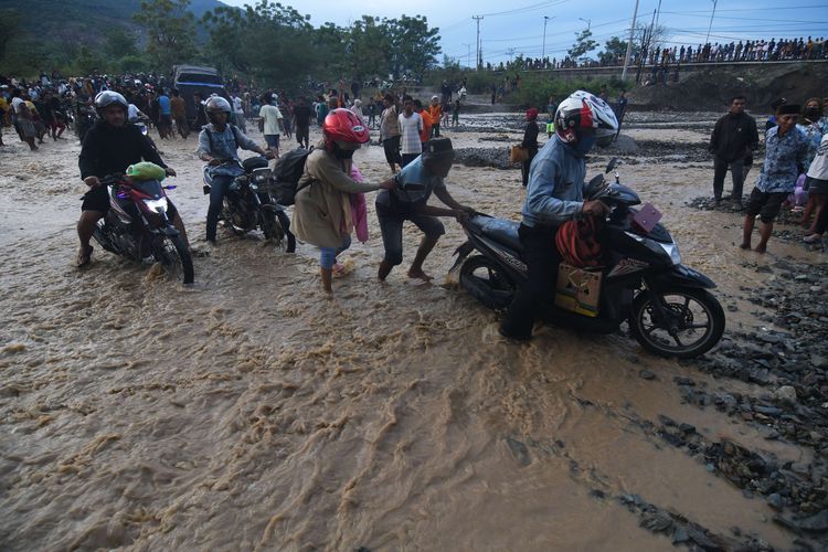 Pengendara melintasi sungai akibat jembatan amblas dan tidak dapat dilalui di Kelurahan Buluri di Palu, Sulawesi Tengah, Jumat (7/4/2023). Jembatan pada jalur penghubung Kota Palu dan Donggala hingga ke Sulawesi Barat dan Sulawesi Selatan serta menjadi salah satu jalur utama bagi pemudik tersebut terputus sehingga pengguna jalan terpaksa melintasi sungai.