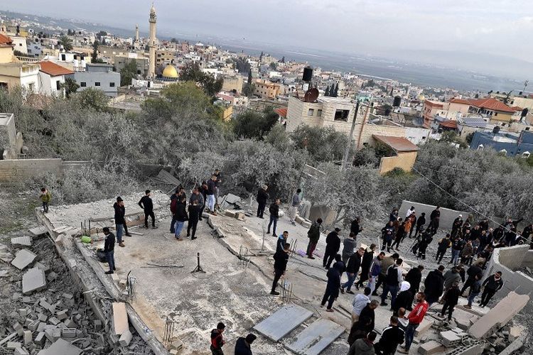 Warga Palestina berkumpul di reruntuhan sebuah rumah Palestina yang dihancurkan oleh pasukan Israel, di desa Silat al-Harithiya dekat kota titik nyala Jenin di Tepi Barat yang diduduki, pada 8 Maret 2022.